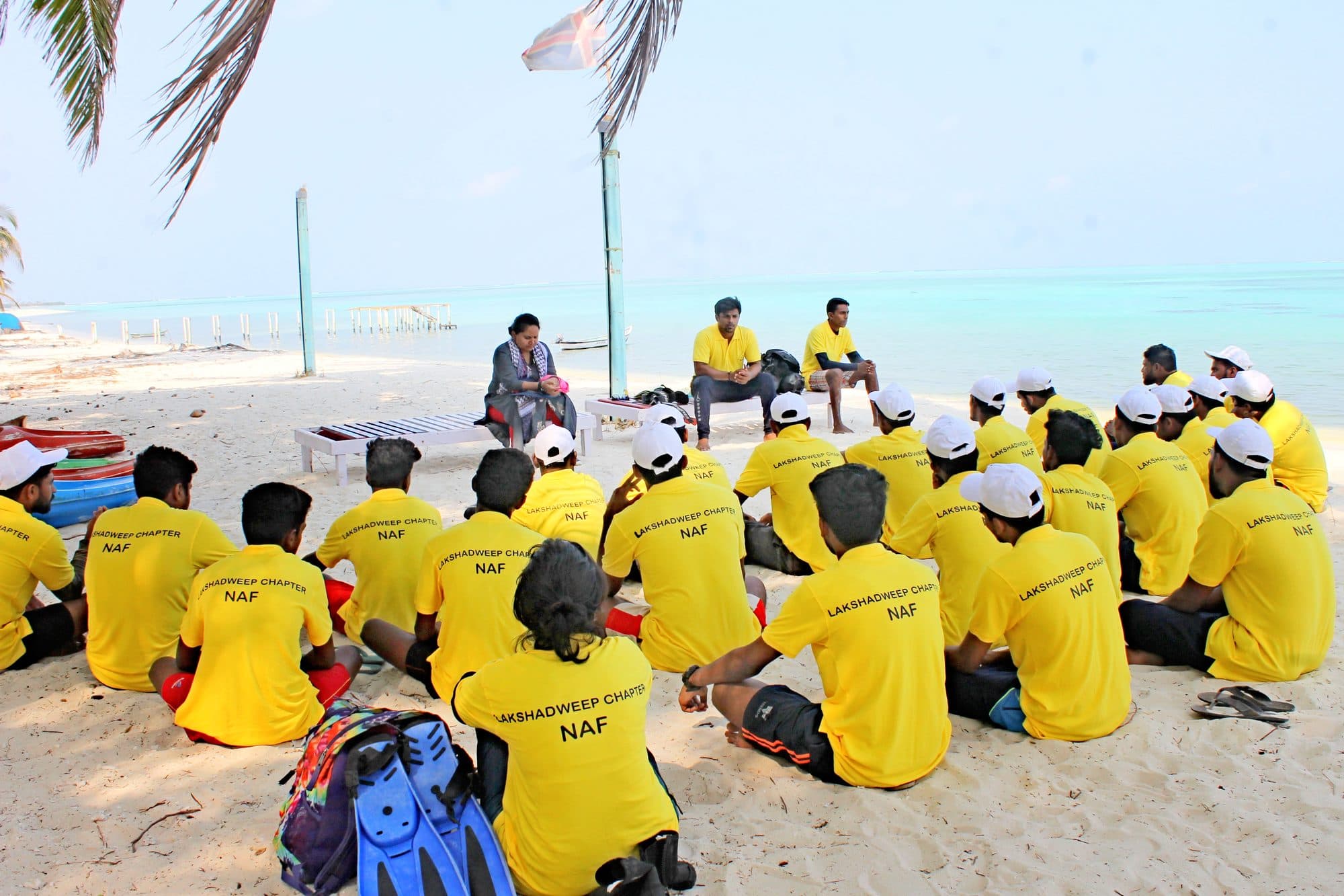 Camp participants seated on the sand for a theory session
